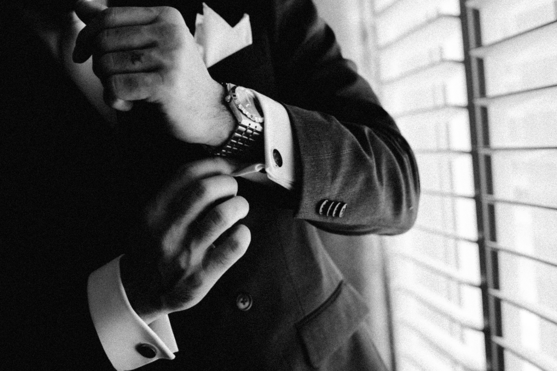 Groom fastening cufflinks in black and white